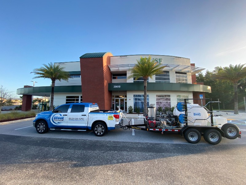Cleaning agency pickup tows powerful pressure washing equipment in front of commercial building