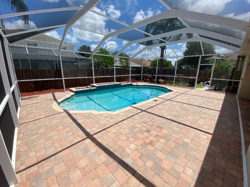 Swimming pool in a glass enclosure with stone and brick surface thoroughly cleaned using pressure washing