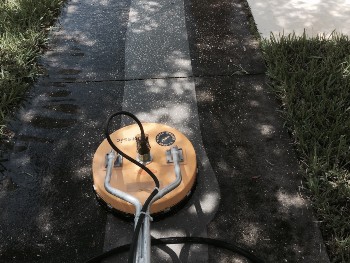 Rotary pressure washer cleaning the middle part of the dirty sidewalk