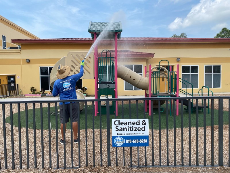 Public playground cleaned by a technician using a high-pressure washer