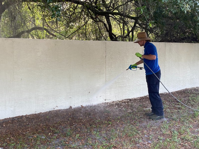 Exterior cleaning agency staff cleans dirty wall using pressure washing equipment