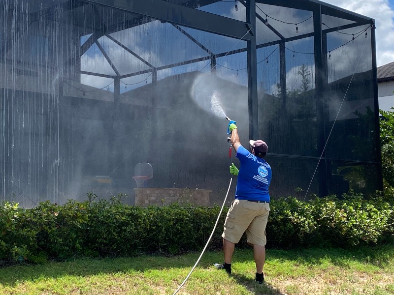 Cleaning employee pressure washes glass solarium thoroughly