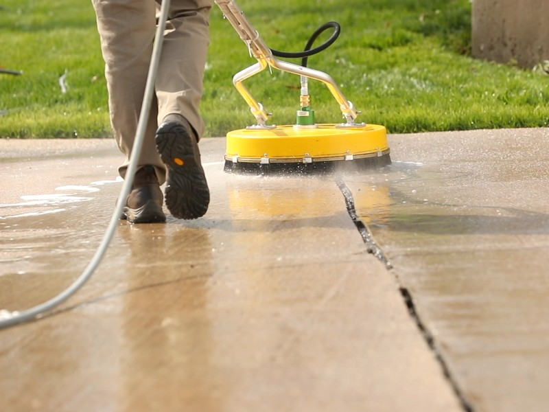 Cleaning expert uses a rotary pressure washer to clean concrete floor